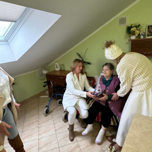 Opiekunowie wręczają kobiecie podarunek