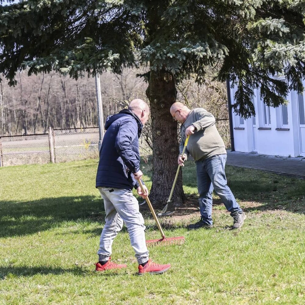 Pracownicy DPS grabią trawnik